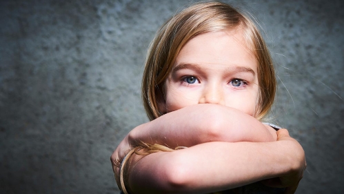 Child crossing arms over face