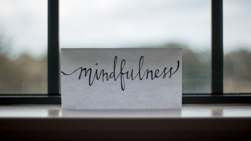Card on a windowsill that reads mindfulness in cursive