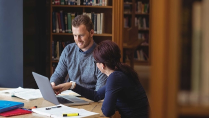 Two students studying in front of bookcase