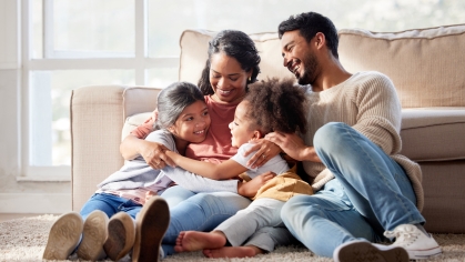 happy Hispanic family hugging in living room