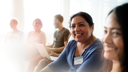 Close up of group of people smiling and participating in community meeting