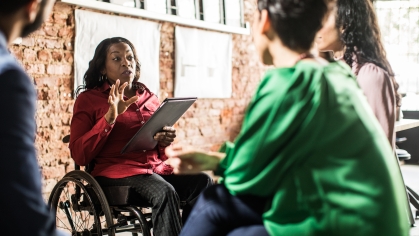 woman holding binder talking to small group