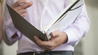 business man holding and reviewing binder