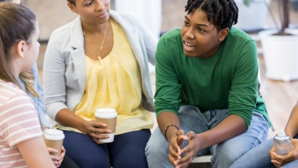 adult woman sitting with group of adolescents