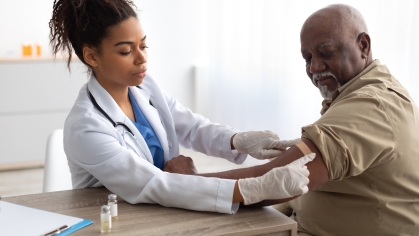 Provider applying bandaid to arm of older patient