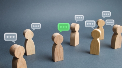 Wodden figures positioned in a group with talk bubbles coming from each figure