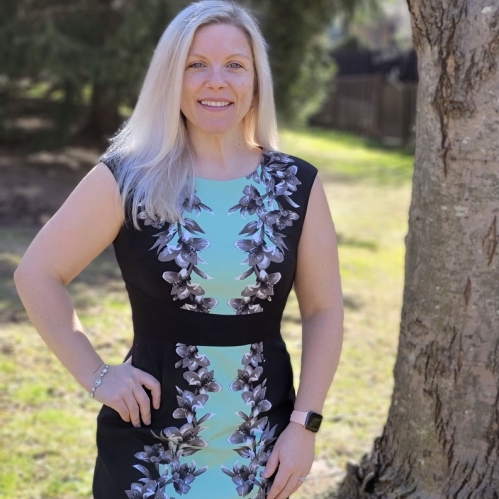 Melissa Shermer outside in front of tree in blue and black dress