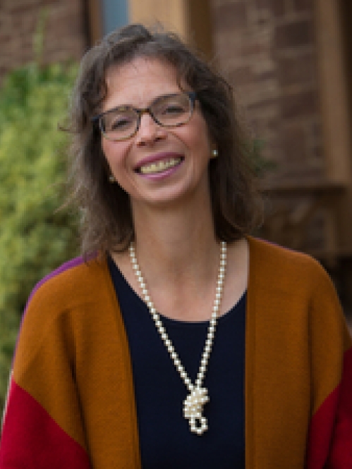 White woman with a cardigan sweater and necklace smiling