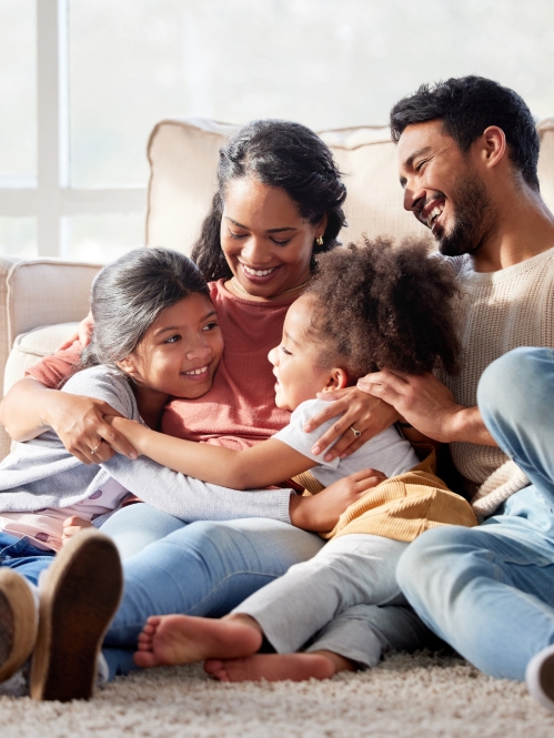happy Hispanic family hugging in living room