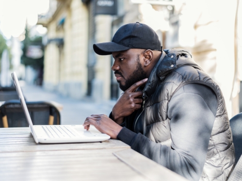 Guy sitting in front of PC at outdoor cafe