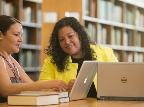 Two female studetns sitting in library 