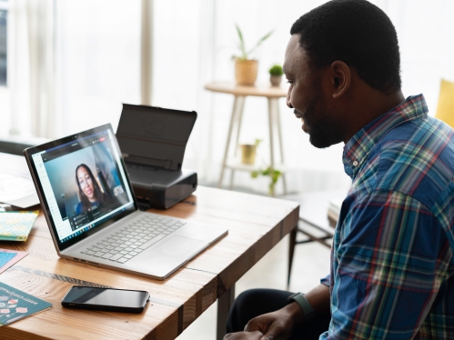 Two people talking over video chat. One in person and one is on the laptop screen