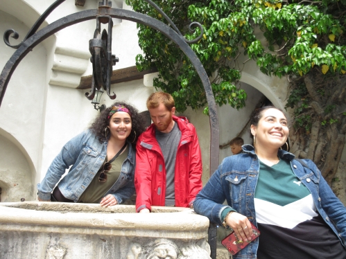 Three young people standing with an old stone well