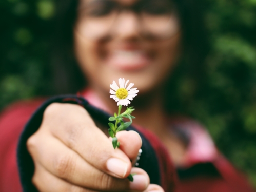 Blurry person in the backgroud holding a flower in the foreground