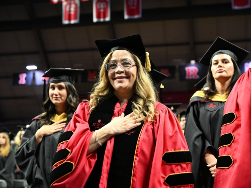 Photo of DSW Student in red regalia and hand over their heart for the pledge of allegence